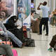 Travelers wait near a closed down terminal at the Miami International Airport on Saturday, Jan. 12, 2019, in Miami. The partial government shutdown is starting to strain the national aviation system, with unpaid security screeners staying home, air-traffic controllers suing the government and safety inspectors off the job. (AP Photo/Brynn Anderson)